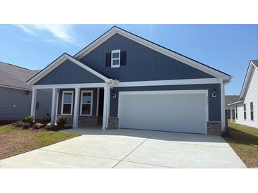 Charming blue one-story home features a two-car garage, a well-manicured lawn, and a inviting front porch at 1428 Winding Creek Way, Myrtle Beach, SC 29588