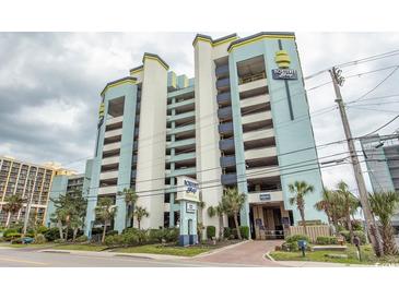 Modern condo building with a parking garage, beautiful landscaping, and tropical palm trees at 6804 Ocean Blvd. N # 625, Myrtle Beach, SC 29572