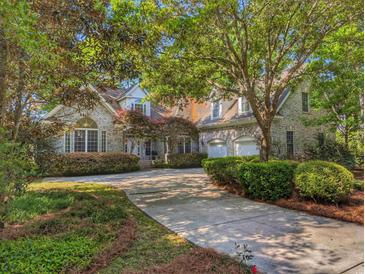 Beautiful exterior with a long driveway and attached garage nestled among mature trees and landscaping at 710 Masters Dr., Pawleys Island, SC 29585