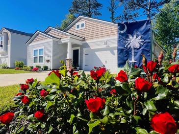 Charming home with beautiful red roses and a South Carolina state flag in the front yard at 147 Marsh Deer Place, Surfside Beach, SC 29575