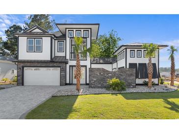 Beautifully designed modern home with a stone facade, manicured lawn, and a two-car garage at 100 Serenity Point Dr., Little River, SC 29566