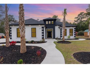 Striking home features a white exterior with black accents, landscaped yard, and inviting walkway to the front door at 1559 Old Tram Rd., Little River, SC 29566