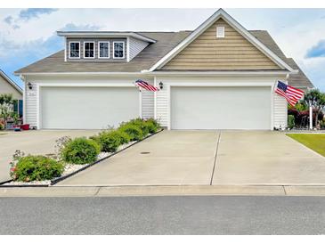 Charming home featuring a spacious two-car garage, adorned with American flags, and a well-maintained front yard at 1856 Melville Ct., Little River, SC 29566