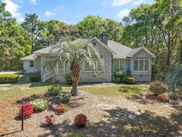 Charming single-story home featuring a brick facade, manicured landscaping, and mature trees at 321 Heather Ct., Sunset Beach, NC 28468