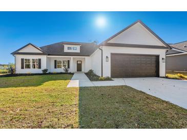 Charming single-Gathering home with well-manicured lawn, brown garage door, and white siding at 4016 Macks Rd, Aynor, SC 29511