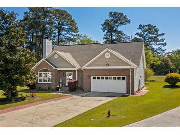 Charming brick home with attached garage, manicured lawn, mature trees, and inviting curb appeal on a sunny day at 414 Staghorn Ln., Longs, SC 29568