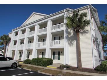 Three-story condo building featuring white siding, columned balconies, and a palm tree in the yard at 5020 Windsor Green Way # 302, Myrtle Beach, SC 29579