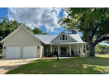 Charming home featuring a metal roof, a two-car garage, and a welcoming front porch perfect for relaxing at 521 Oak Lawn Rd., Georgetown, SC 29440