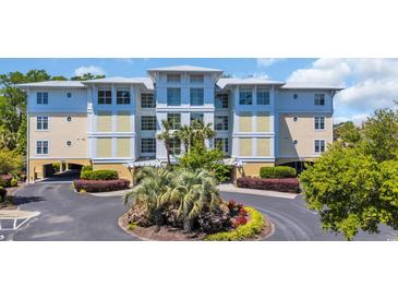 Beautiful condo complex exterior with lush landscaping and a circular driveway with palm trees at 1352 Villa Marbella Ct. # 1-204, Myrtle Beach, SC 29572