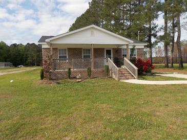 Charming brick home with a covered porch and well-manicured lawn featuring vibrant red flowers at 1465 Dirty Branch Rd., Conway, SC 29527