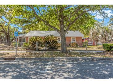 Charming brick home with a metal roof, mature landscaping, and a red shed at 311 Surfside Dr., Surfside Beach, SC 29575