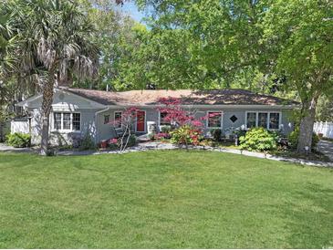 Charming home featuring a lush green lawn, mature trees, and a vibrant red front door creating a welcoming entrance at 412 43Rd Ave. N, Myrtle Beach, SC 29577