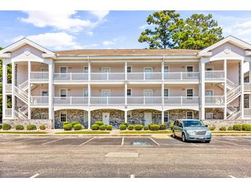 Three-story condo building featuring white trim, multiple balconies, parking, and a well-maintained landscape at 4787 Wild Iris Dr. # 101, Myrtle Beach, SC 29577