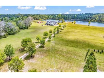Expansive property featuring a modern farmhouse, private lake, and a charming red barn amid rolling green fields at 2300 Tansy Rd., Loris, SC 29569