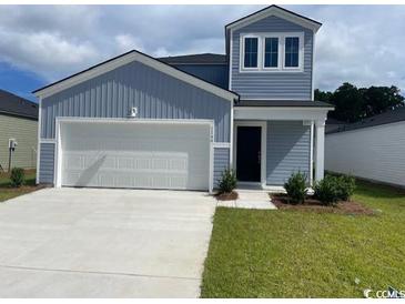 Charming two-story home with blue siding, attached garage and well-maintained lawn at 1166 Silver Perch Place, Sunset Beach, NC 28468