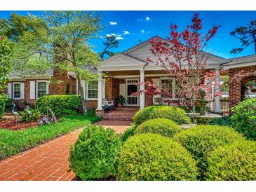 Charming brick home with a lush landscaped yard, brick walkway, front porch, and water fountain at 141 N Gate Rd., Myrtle Beach, SC 29572