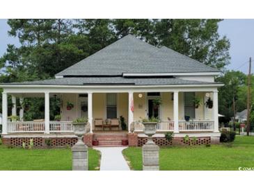 Charming yellow house featuring a welcoming front porch and manicured lawn at 402 Gibson St., Marion, SC 29571