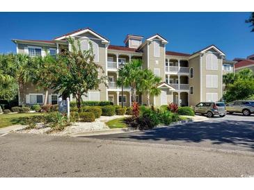 Exterior view of a well-maintained condominium complex with lush landscaping and convenient parking at 4215 Coquina Harbour Dr. # D -2, Little River, SC 29566