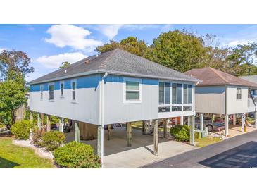 Coastal home featuring a stilt foundation, screened porch, and manicured landscaping at 820 9Th Ave. S, North Myrtle Beach, SC 29582