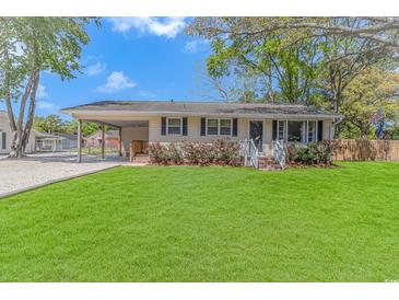 Charming single-story home with a well-manicured lawn, covered parking and vibrant flower bushes lining the front porch at 1931 Jasper St., Georgetown, SC 29440