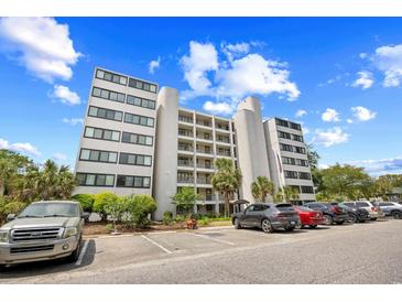 Low-angle view of a multistory condo building with ample parking, landscaping, and beautiful blue sky at 311 71St Ave. N # 3-D, Myrtle Beach, SC 29572