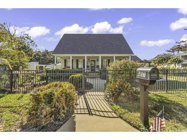 Charming home featuring a well-kept lawn, black fence, and inviting front porch, offering curb appeal at 407 15Th Ave. S, North Myrtle Beach, SC 29582