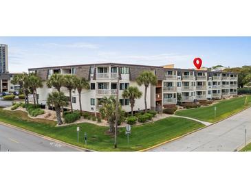 Low-rise condominium complex with landscaped grounds, mature trees, and white exterior at 5601 N Ocean Blvd. # E-304, Myrtle Beach, SC 29577