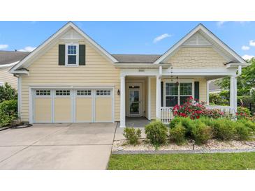 Charming home with a two-car garage, yellow siding, a porch and a beautifully landscaped front yard at 1881 Willowcress Ln., Myrtle Beach, SC 29577
