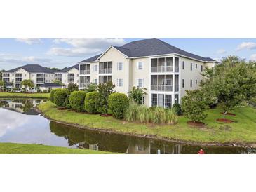 Beautiful exterior view of a condo building with pond, landscaping and screened-in porches at 2090 Cross Gate Blvd. # 202, Surfside Beach, SC 29575