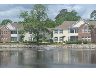 Beautiful waterfront condo building featuring neutral siding, lovely landscaping, and a serene lake view at 22 Woodhaven Dr. # C, Murrells Inlet, SC 29576
