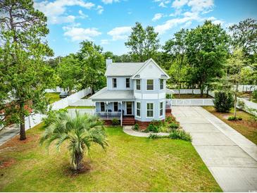 Charming two-story home with a well-manicured lawn, a driveway, a picket fence, and mature trees at 221 Lander Dr., Conway, SC 29526