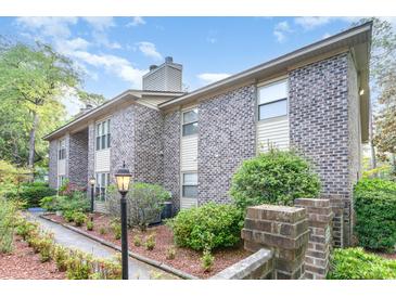 Brick condo building with manicured landscaping, sidewalk, and decorative street lighting on a sunny day at 404 75Th Ave N # G, Myrtle Beach, SC 29572