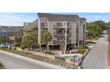 Three-story condo building with multiple balconies and covered parking, surrounded by lush landscaping and street access at 4500 S Ocean Blvd. # 4, North Myrtle Beach, SC 29582