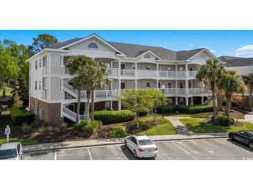 Three-story condo building with white siding, balconies, and palm trees in a well-maintained complex at 5751 Oyster Catcher Dr. # 431, North Myrtle Beach, SC 29582