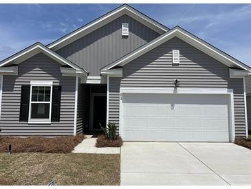 Charming gray home features a white garage door and manicured lawn under a bright blue sky at 624 Muster Field Ct., Conway, SC 29526