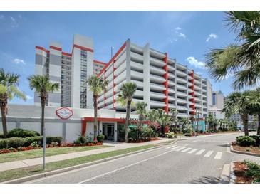 View of a condominium building with a connected parking garage and beautiful tropical landscaping at 7200 Ocean Blvd. N # 664, Myrtle Beach, SC 29572