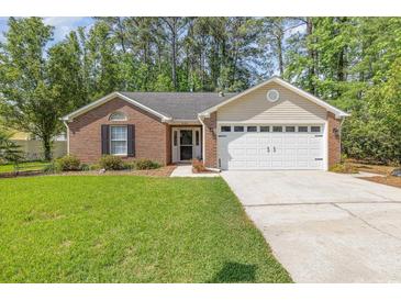 Charming brick home with a well-manicured lawn and a two-car garage at 2405 Brick Dr., Longs, SC 29568