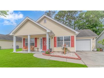 Charming single-story home featuring a well-manicured lawn, red shutters, and a cozy front porch sitting area at 409 Hunley Ln., Myrtle Beach, SC 29577