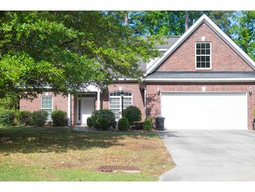 Charming brick home featuring a manicured lawn, mature trees, and an attached two-car garage at 4266 Arabella Way, Little River, SC 29566