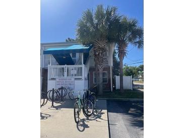 Exterior of building with bike rack, reserved parking sign, and lush palm trees at 804 12Th Ave. S # 218, North Myrtle Beach, SC 29582