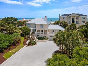 Stunning coastal home with a white facade, metal roof, lush landscaping and scenic ocean views at 109 Pioneer Loop, Georgetown, SC 29440