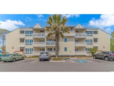 Attractive multi-story condo building with large balconies and lush palm tree in front at 1100 Possum Trot Rd. # H136, North Myrtle Beach, SC 29582