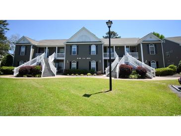 Low-angle view of a condo complex featuring multiple units with white staircases and lush lawn at 1101 Peace Pipe Pl. # 201, Myrtle Beach, SC 29579