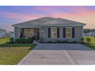 Charming single-story home featuring a well-manicured lawn, neutral siding, and a cozy front porch area at 231 Jeff Waters Circle, Longs, SC 29568