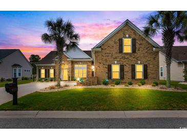 Charming brick home with a well-manicured lawn and palm trees, set against a vibrant sunset sky at 4311 Grovecrest Circle, North Myrtle Beach, SC 29582