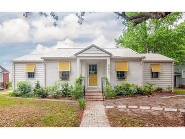 Charming home featuring a metal roof, brick walkway, yellow door, and lovely landscaping at 640 Willowbank Rd., Georgetown, SC 29440