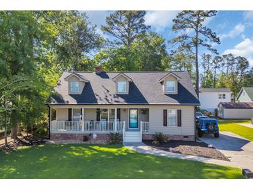 Charming home with a welcoming front porch, lush lawn, and driveway featuring a blue Jeep at 6864 Woodhaven Dr., Myrtle Beach, SC 29588