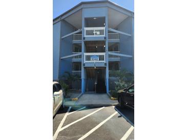 Three-story condominium building featuring blue siding, white railings, palm trees, and convenient parking at 9540 Shore Dr. # 1N, Myrtle Beach, SC 29572