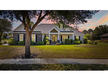 Charming single-story home with stone accents, landscaped yard, and inviting front porch at dusk at 1028 Whooping Crane Dr., Conway, SC 29526
