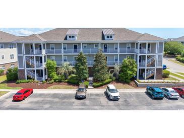 Three-story condo building featuring multiple balconies, a landscaped courtyard, and ample parking at 200 Castle Dr. # 1369, Myrtle Beach, SC 29579